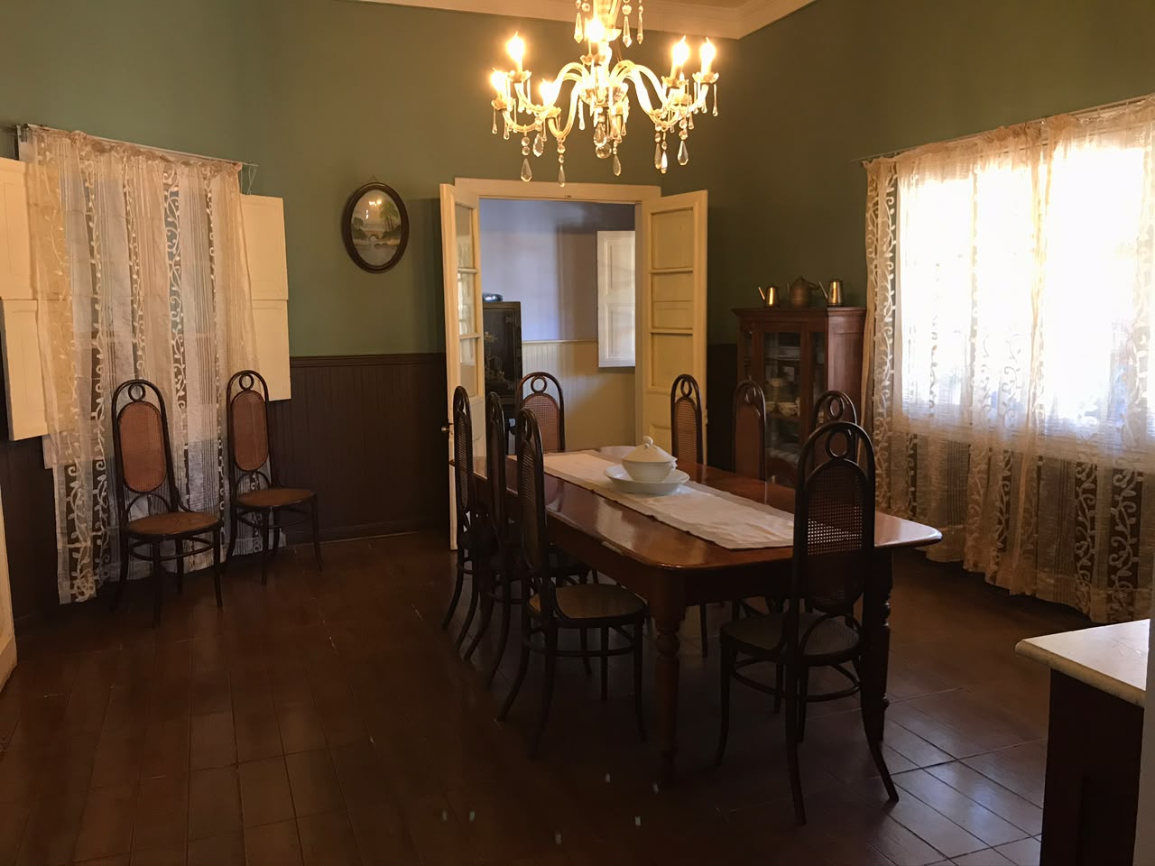 Comedor familiar verde de Casa Vallereggia con mesa y lámpara de cristal