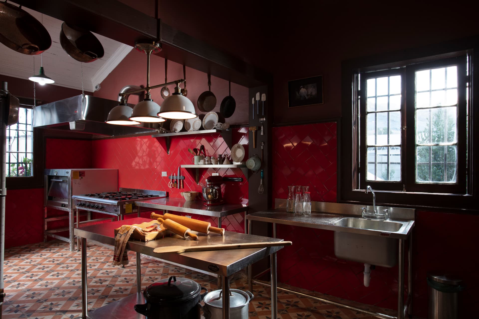 Cocina roja de Casa Vallereggia con mesones de acero y cobre colgado