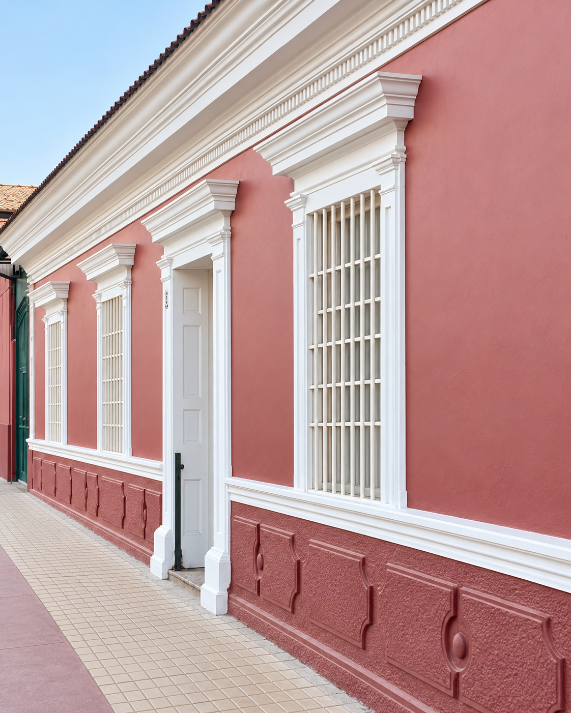 Fachada restaurada de Casa Vallereggia, con molduras blancas sobre muros terracota