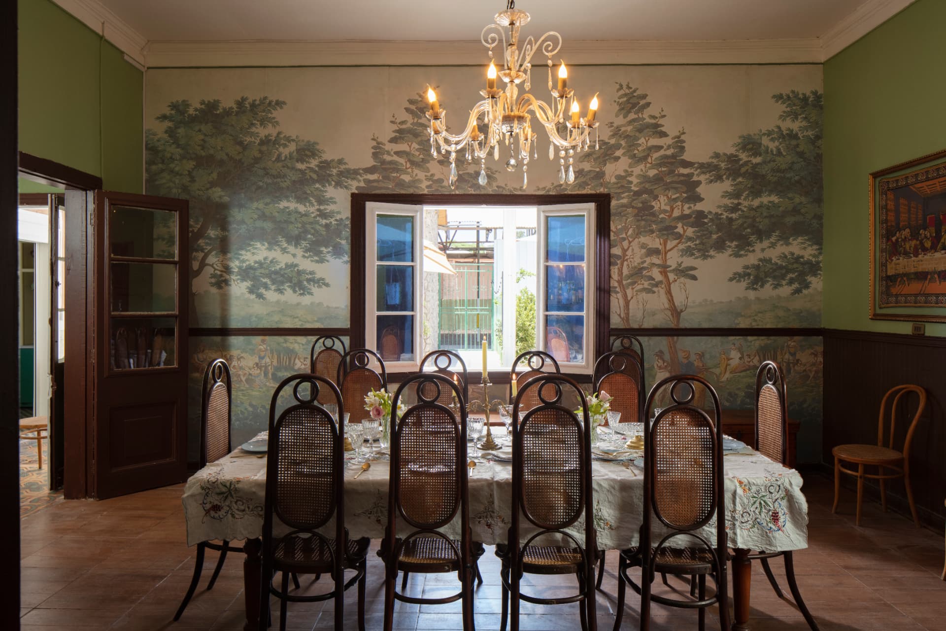 Gran comedor de Casa Vallereggia con mural, lámpara de cristal y mesa preparada