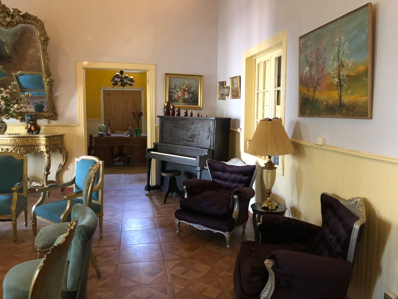 Salón histórico de Casa Vallereggia con piano, sillones y pinturas familiares
