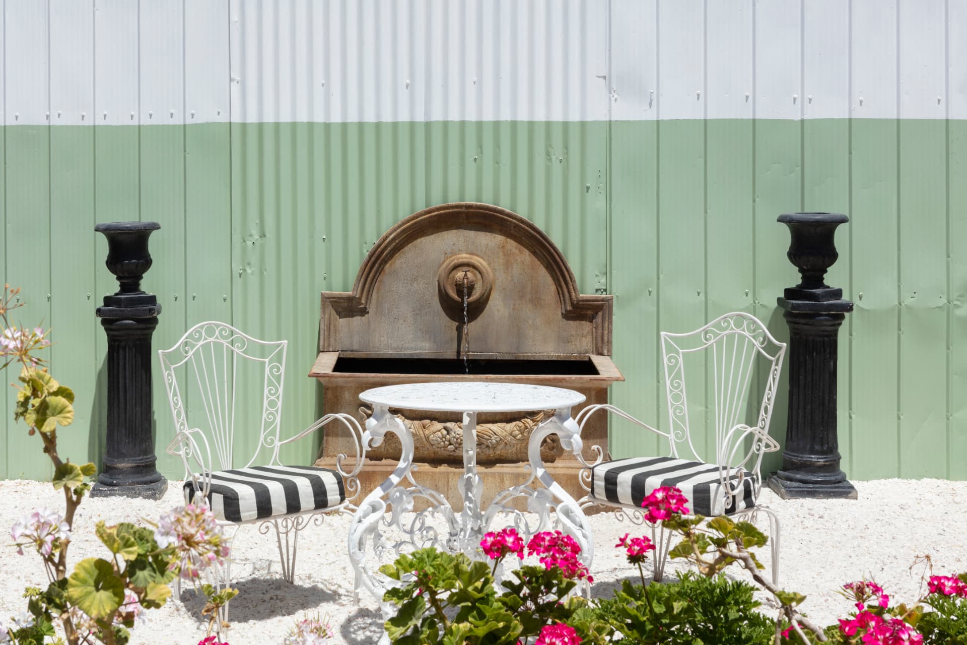 Terraza de Casa Vallereggia con fuente, mesa de mármol, sillas blancas y flores